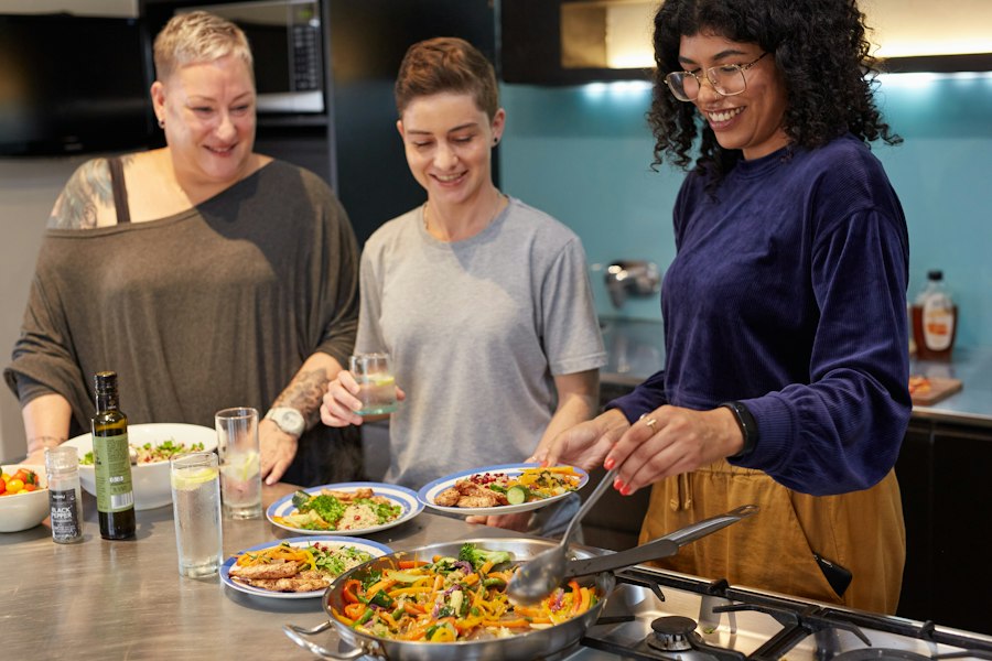 Three women cooking and serving food together